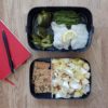 Lunchbox avec une partie contenant la salade aux endives et aux pommes et une autre partie contenant le filet de bar brocoli et pesto carnet rouge et stylo
