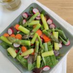 Salade composée d'un mélange de mesclun, roquette, pousses d'épinards, asperges vertes, carotte et radis dans une assiette creuse carrée verte