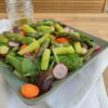 Salade composÃ©e d'un mÃ©lange de mesclun, roquette, pousses d'Ã©pinards, asperges vertes, carotte et radis dans une assiette creuse carrÃ©e verte